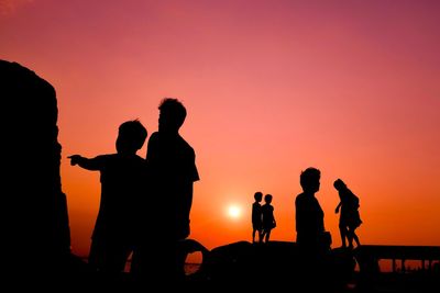 Silhouette people against orange sky