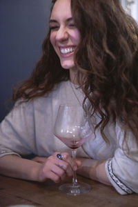 Close-up of cheerful young woman holding wineglass at table