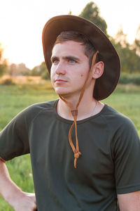 Young man farmer in cowboy hat at agricultural field on sunset with sun flare. closeup portrait 