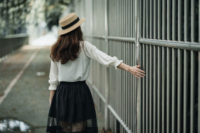 Rear view of woman standing against railing