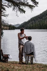 Man with umbrella on lake against trees