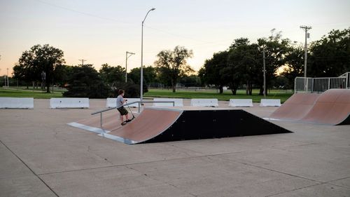 Full length of boy riding push scooter at skateboard park during sunset