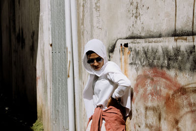 Portrait of man wearing sunglasses standing against wall