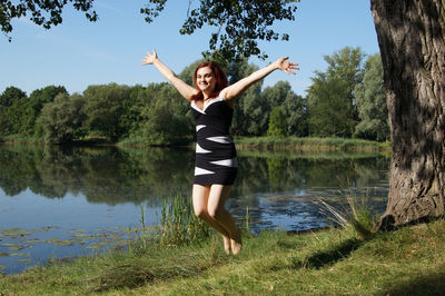 Portrait of young woman jumping at lake