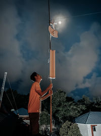 Man holding traditional windmill against sky