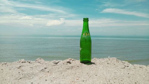 Close-up of bottle on beach against sky