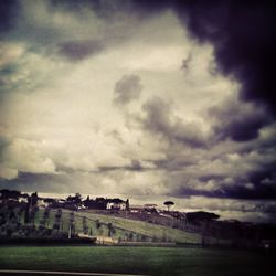 View of field against cloudy sky