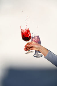 Hand holding red wine against white background