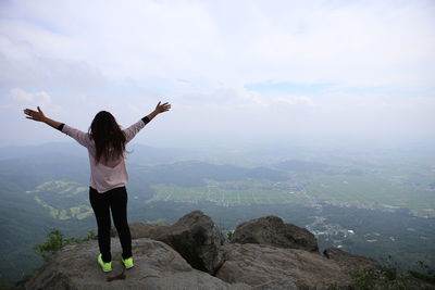 Rear view of woman standing on mountain against sky