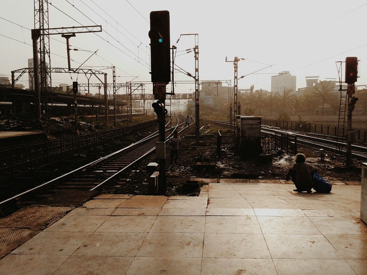 men, lifestyles, building exterior, clear sky, sky, railroad track, built structure, city, full length, rear view, architecture, leisure activity, street light, transportation, person, silhouette, railing, city life