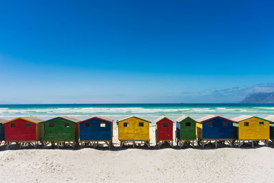 Beach umbrellas by sea against blue sky