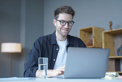 Smiling businessman using laptop at office