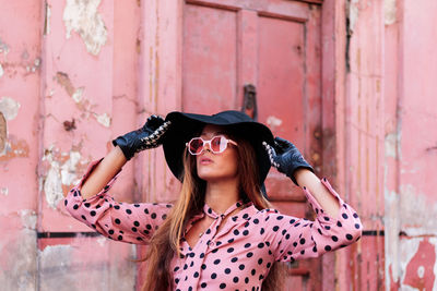 Close-up portrait of model in pink dress and gloves holding black hat in london