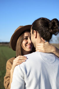 Portrait of smiling young couple against blue sky