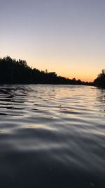 Surface level of lake against sky during sunset