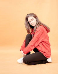 Portrait of young woman sitting against wall