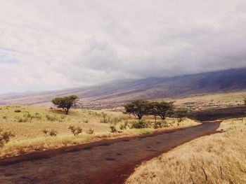 Country road against cloudy sky