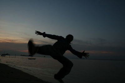 Silhouette of man jumping at sea