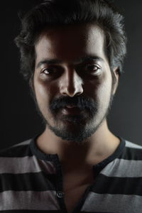 Portrait of young man standing against black background