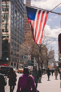 American flag hanging over people in city