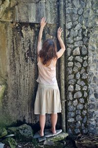 Rear view of woman standing by wall