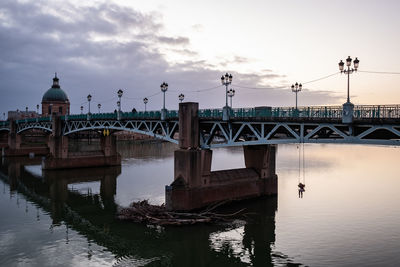 Arch bridge over river against sky during sunset