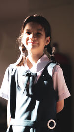 Portrait of a smiling girl standing against wall