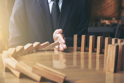 Close-up of businessman playing domino on desk