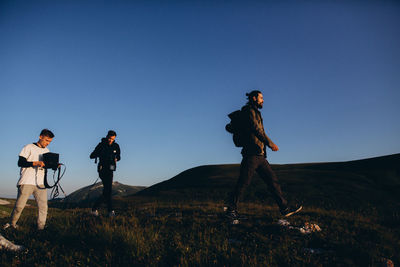 Men standing on field against clear sky