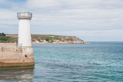 Lighthouse by sea against sky