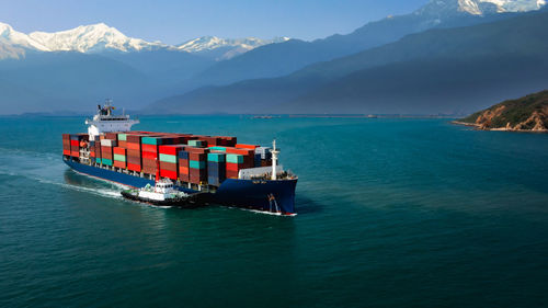 Aerial view container cargo ship and tugboat floating carrying commercial container in import export 