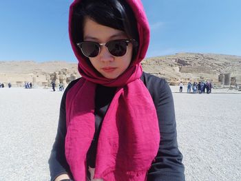 Young woman wearing sunglasses standing on field against sky