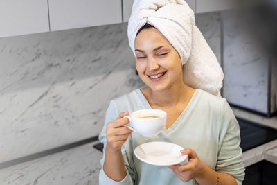 Smiling woman holding coffee cup at home