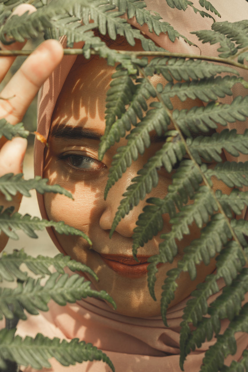 CLOSE-UP PORTRAIT OF YOUNG WOMAN WITH RED LEAVES