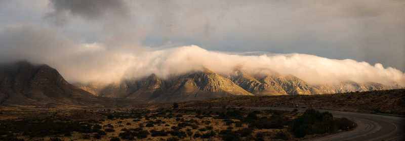 Scenic view of mountains with low clouds inversion against sky during moody sunrise