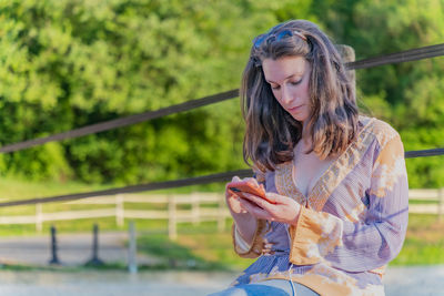 Portrait of young woman in nature checking news on her mobile phone