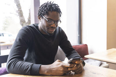 Young man text messaging through smart phone in cafe