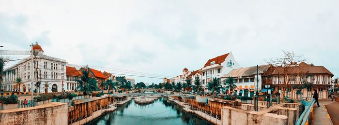 Panoramic view of buildings by canal against sky