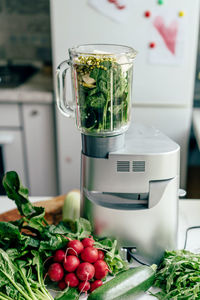 Bowl of blender with herbs and vegetables. cooking a green spring smoothie. healthy eating concept.