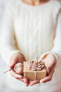 Woman holds present and coil of thread with crochet hook. example of diy ways to pack cristmas gifts