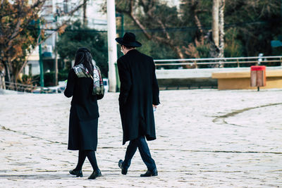 Rear view of friends walking on footpath