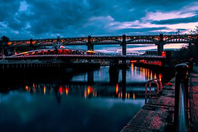 Illuminated bridge over river against sky at dusk