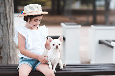 Cute stylish baby girl 4-5 year old sitting with pet dog in park outdoors. togetherness. friendship.