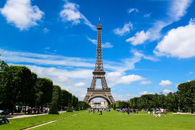Eiffel tower by park in city on sunny day
