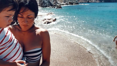 Portrait of woman carrying boy on beach