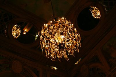 Low angle view of illuminated light bulb hanging from ceiling