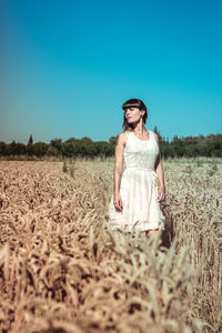 Young woman standing on field against clear sky