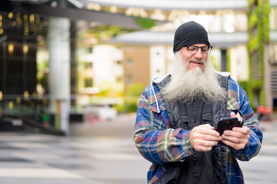 Portrait of man with mobile phone standing in city