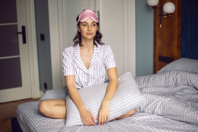 Woman in pajamas and with a sleep mask on the bed in the bedroom