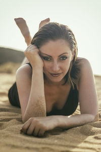 Portrait of young woman lying down against sky